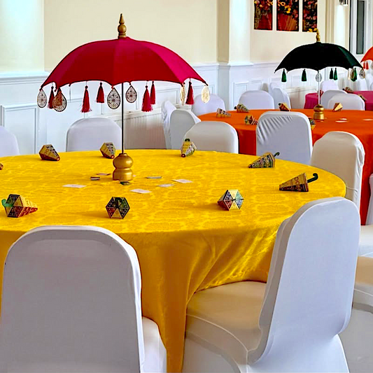Decorative table setting with colorful umbrellas and tablecloths in a room.